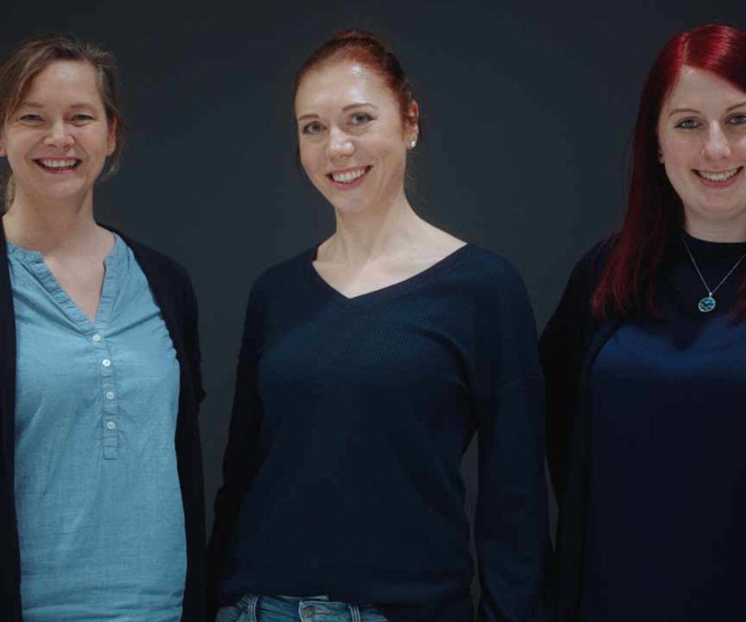 Imagefilm Hannover. Das Team von Bacta Implants steht vor einer dunklen Wand und lächelt in die Kamera. Titelbild des von 52° Film produzierten Videoporträts für hannoverimpuls.