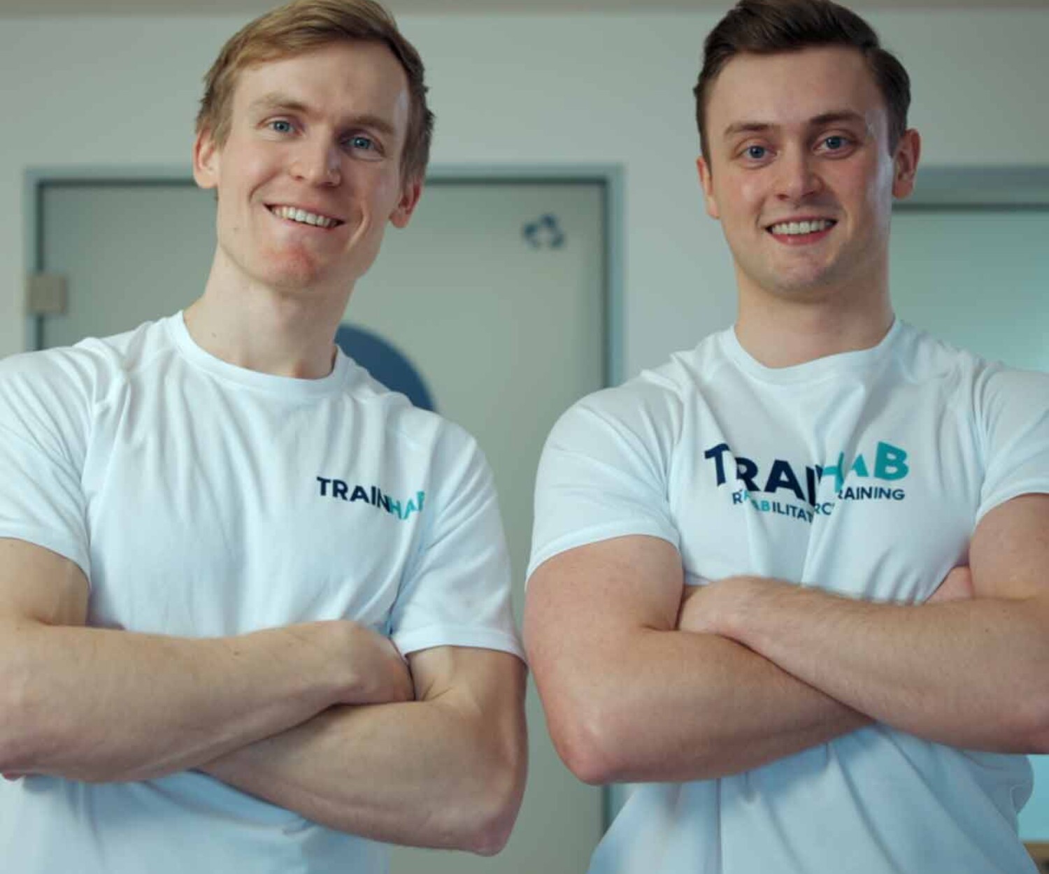 Das Team von TrainHub steht freundlich in einem Sportraum und schaut in die Kamera. Titelbild des von 52° Film produzierten Videoporträts für hannoverimpuls.