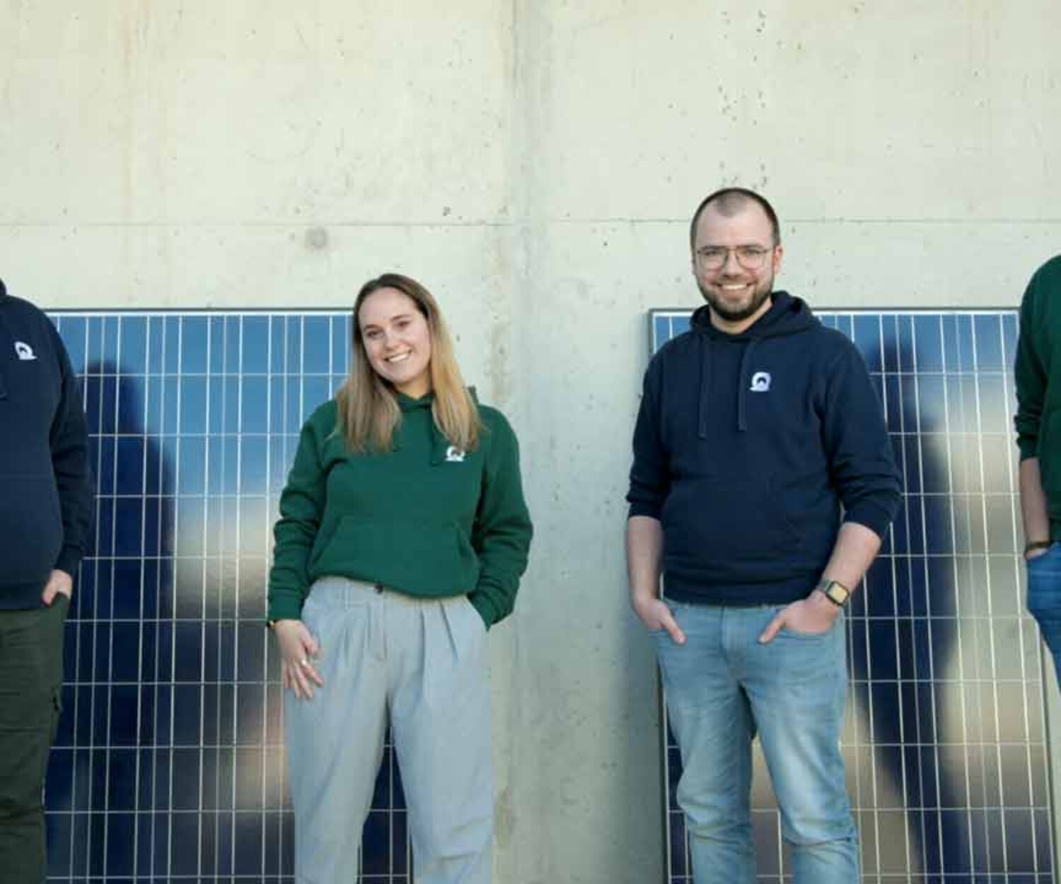 Videoportrait Hannover. Das Team von Marcley steht vor zwei an einer Wand lehnenden Solarpanels und schaut freundlich in die Kamera. Titelbild des von 52° Film produzierten Videoporträts für hannoverimpuls.