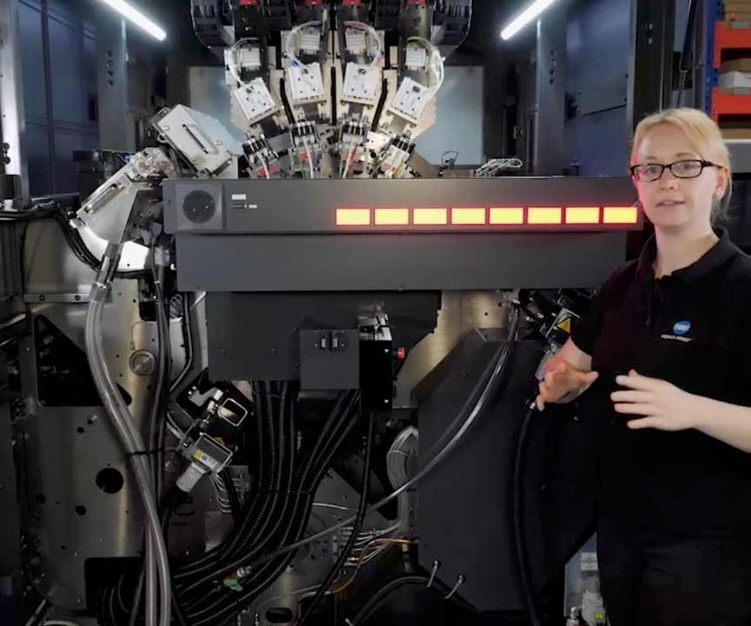 Produktvideo Hannover Mitarbeiterin Laura von Konica Minolta steht vor einer Druckmaschine und erklärt deren Funktionen. Titelbild eines von 52° Film produzierten Produktvideos.