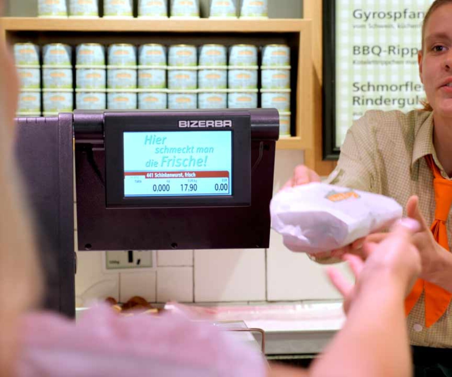 Eine Verkäuferin vom Wurst-Basar übergibt einer Kundin Ware über den Tresen. Recruitingvideo-Produktion Hannover von 52° Film.