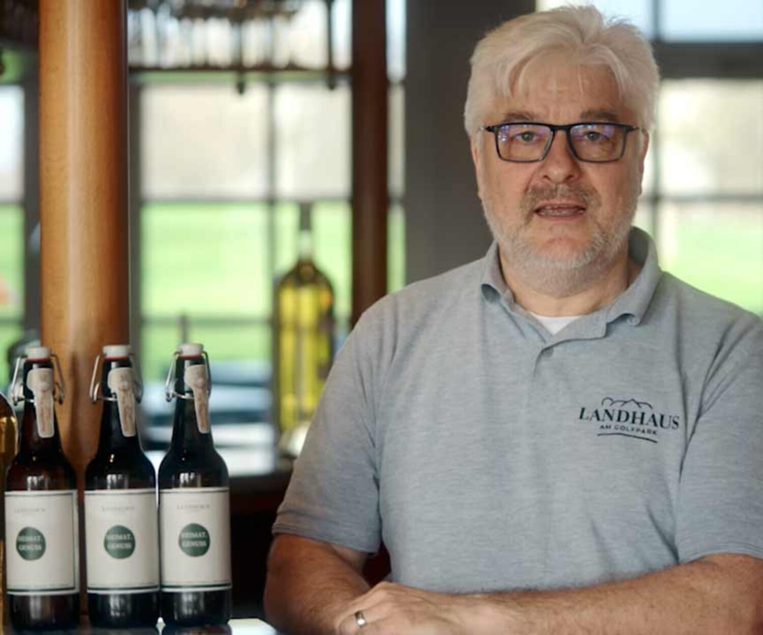 Imagefilm Hannover -Der Gastwirt Marko Nolden vom Landhaus am Golfpark steht am Tresen und erklärt die Vorteile der WhatsApp-Integration von Vendou. Titelbild des von 52° Film produzierten Videoporträts für hannoverimpuls.